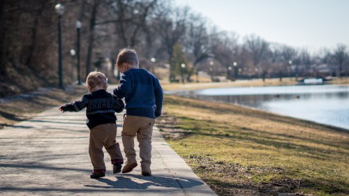 dwaj chłopcy stojący tyłem w parku na spacerze 